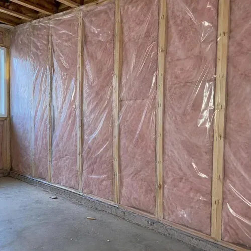 Vapour barrier stapled over insulated wall studs during insulation and drywall work in Kingston, ON