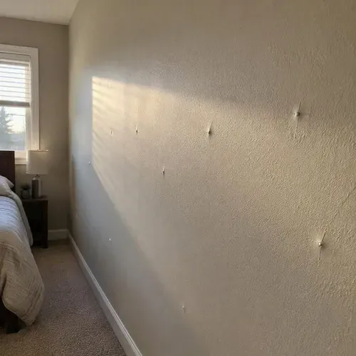 Nail pops showing across a bedroom wall on a drywall repair job in Kingston, ON