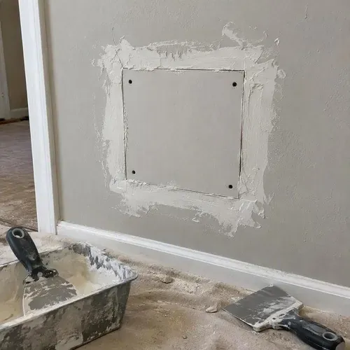 Square drywall patch fitted into a damaged wall during drywall repair in Kingston