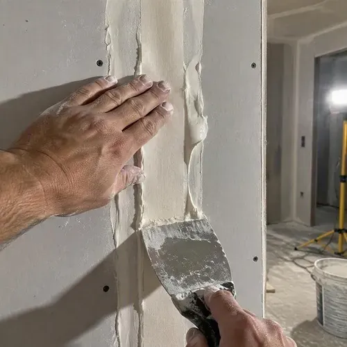 Paper tape pressed into wet compound seam during drywall taping and finishing in Kingston, ON