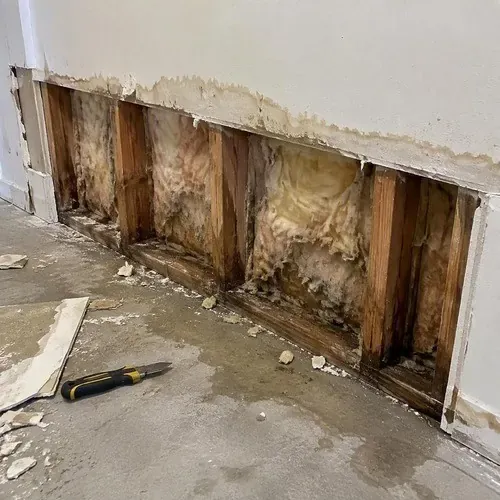 Wet drywall cut away to expose soaked studs during water damage drywall repair in Kingston